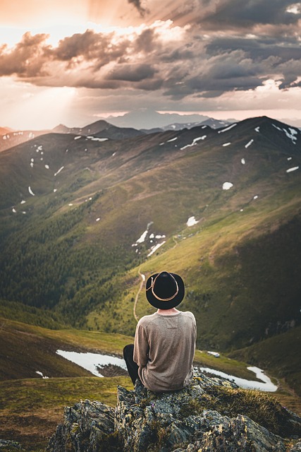 hombre sentado frente a las montañas viendo el atardecer